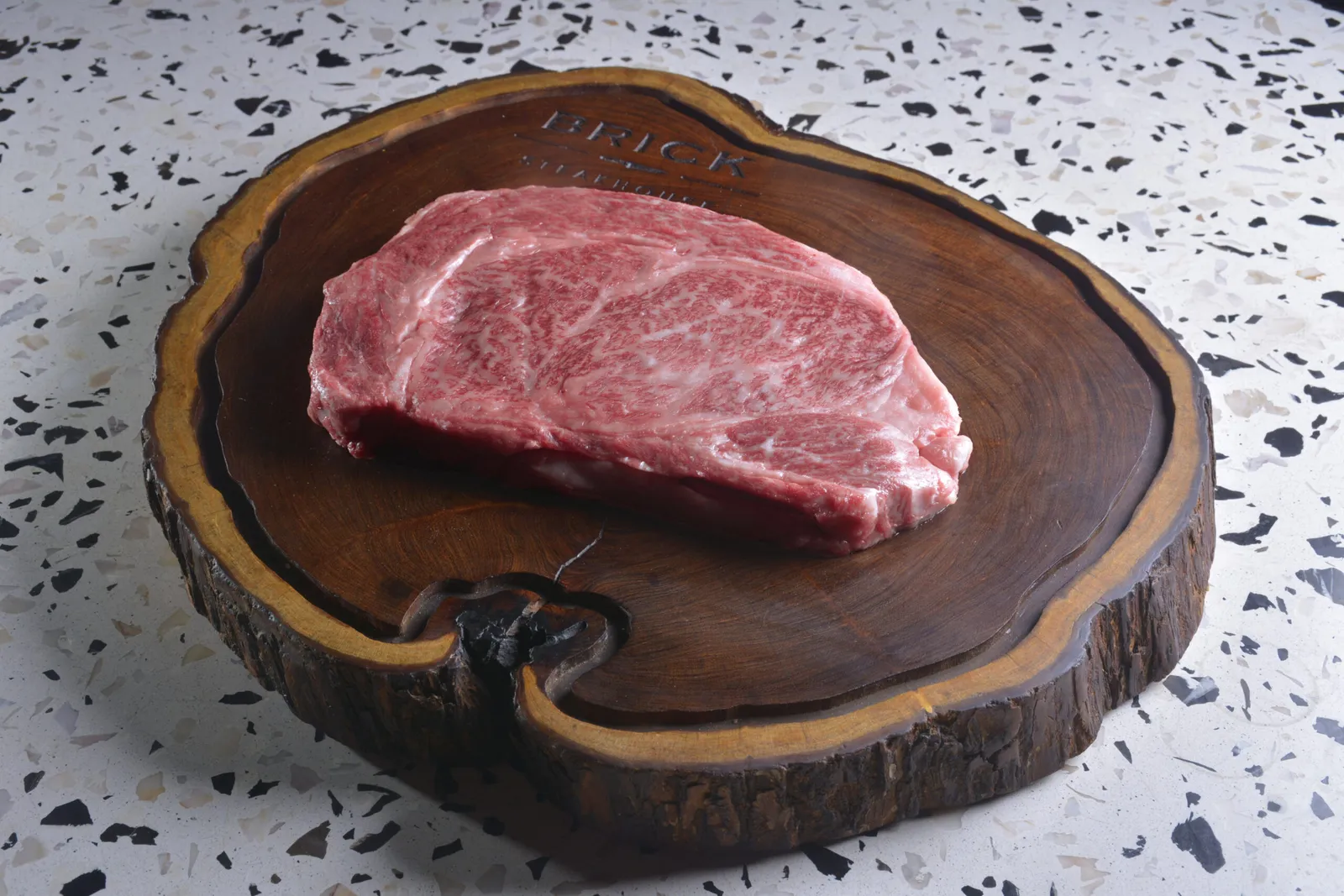 Corte wagyu crudo y marmoleado sobre la tabla de madera de Brick